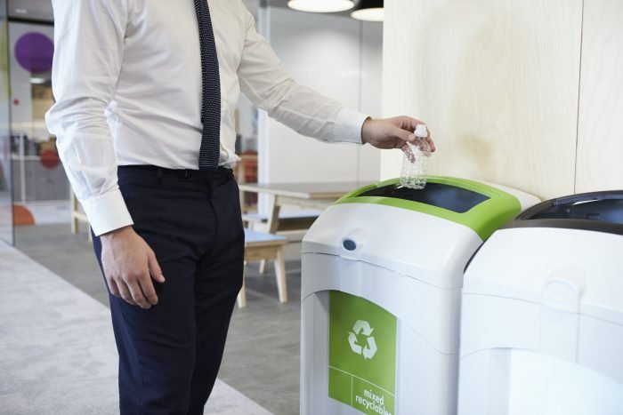 Mies lajittelee kierrätysmerkkien mukaan